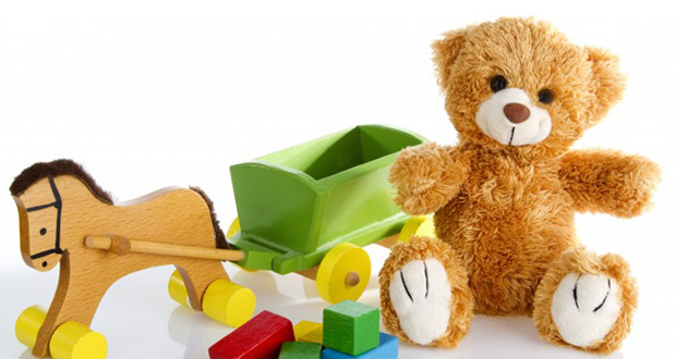 Ein Teddybär, ein Holzpferdchen und Bauklötze vor weißem Hintergrund