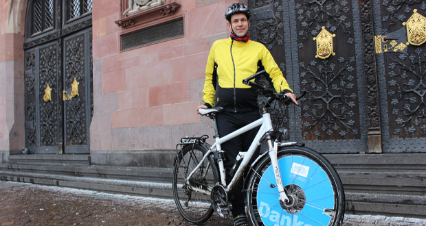 Timo Michael mit seinem weißen City-Bike. In den Speichen klemmt ein "Danke"-Werbemittel von Klimaschutz Frankfurt.