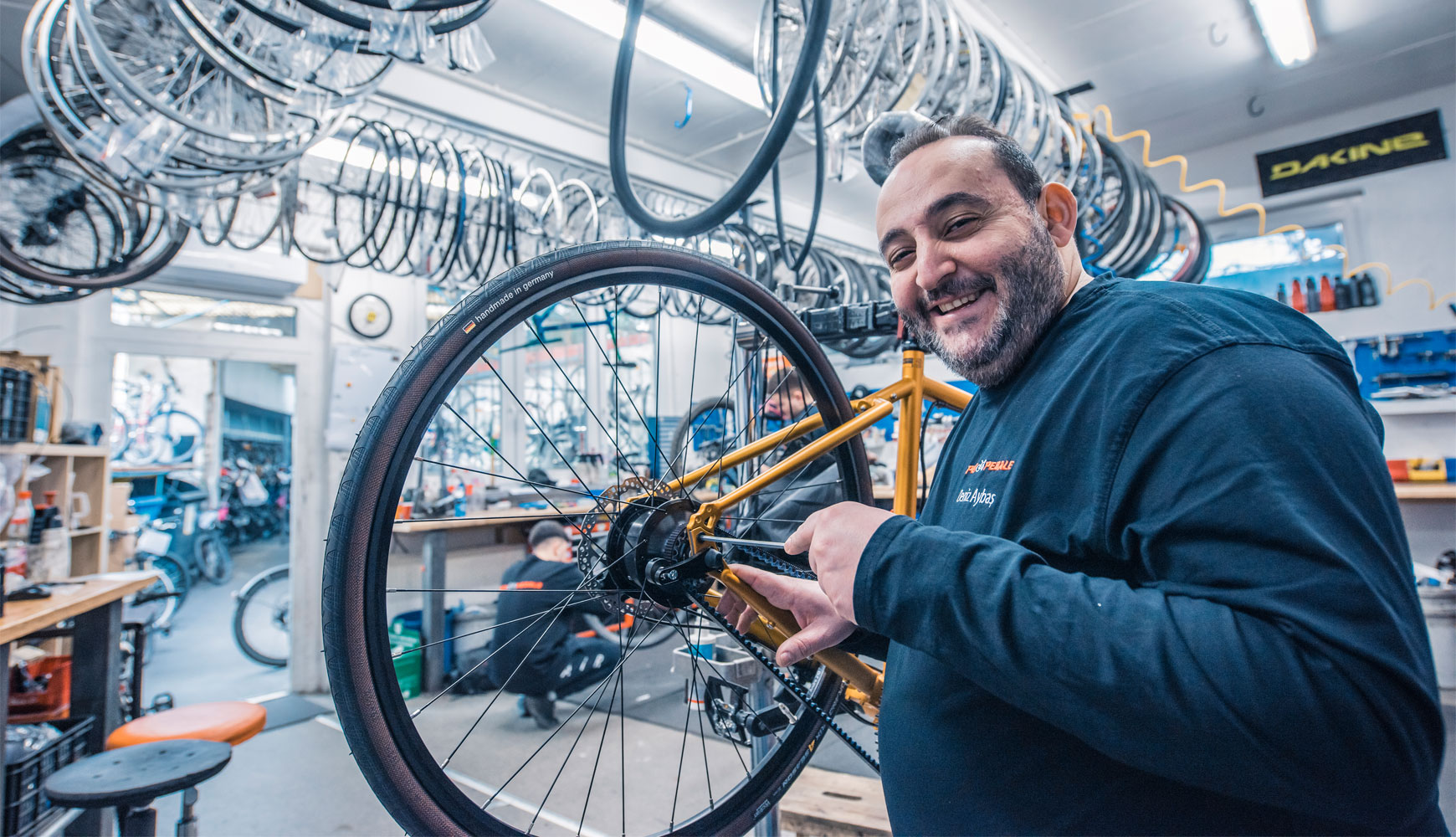 Daniz Aybaş von Per Pedale setzt in der Werkstatt ein Hinterrad ein.