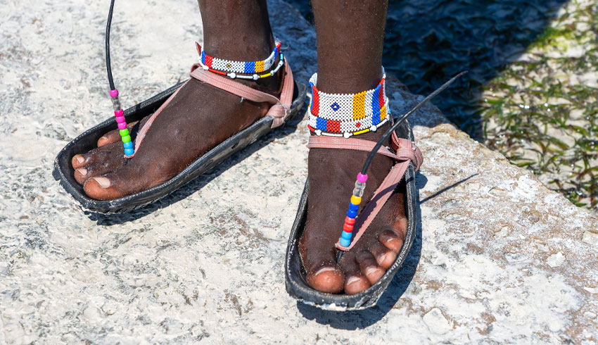 Ein Fußpaar trägt aus Reifen gefertigte Sandalen.
