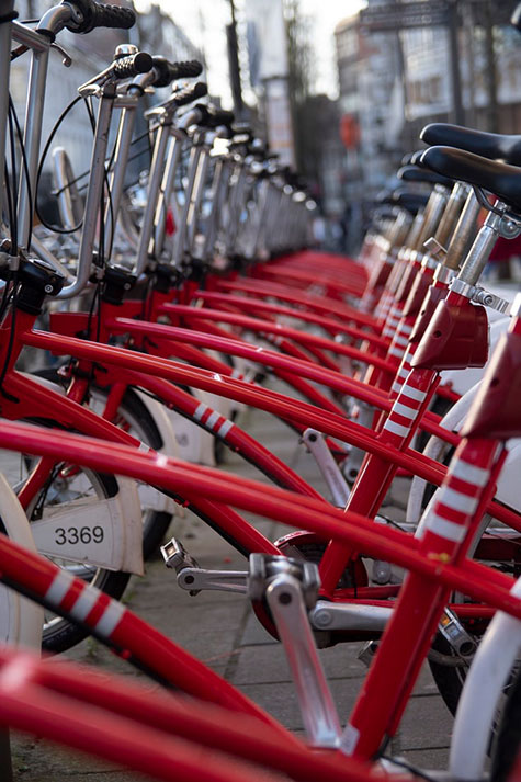 Viele rote Leih-Fahrräder stehen gegliedert in einer Reihe