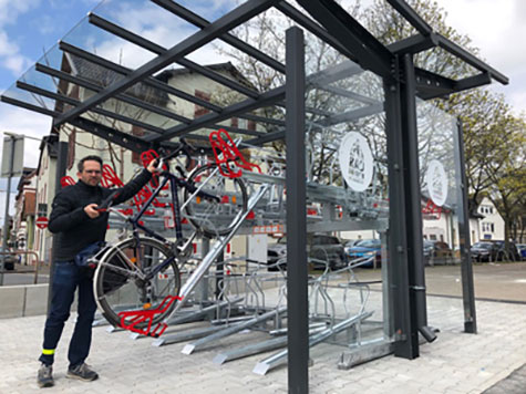Ein Mann parkt ein Fahrrad in einem überdachten Fahrrad Parkplatz